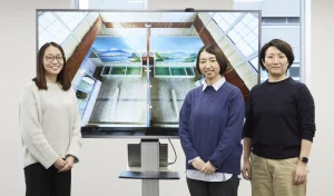 左から福井久美子さん、田口充奈子さん、小林愛恵さん。江戸東京たてもの園の銭湯「子宝湯」の3Dデータを背景に
