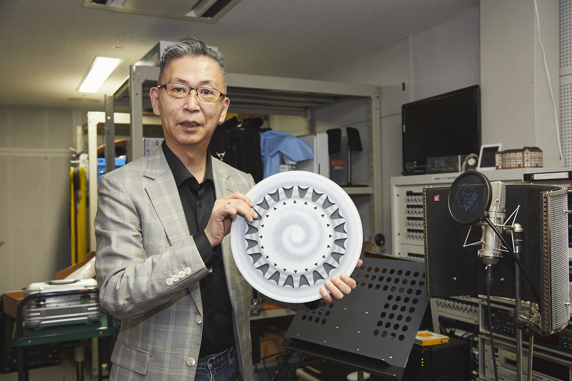 舞台管理担当係長の石丸耕一さん。効果音の収録や、各ホールへの音の提供を行うサーバーが設置された音響工房にて。手に持っているのは、水の音をつくり出す道具