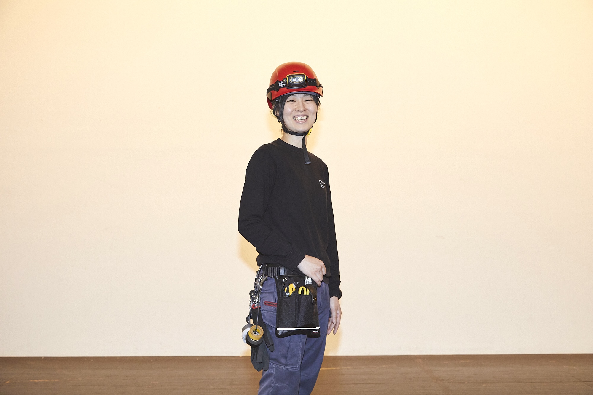 舞台管理担当主事の松島千裕さん。ヘルメットをかぶり、腰に道具を下げて劇場内を縦横無尽にかけめぐる一方、制作スケジュールの管理や舞台の配置計画ではCADをひくなどデスクワークも多い仕事